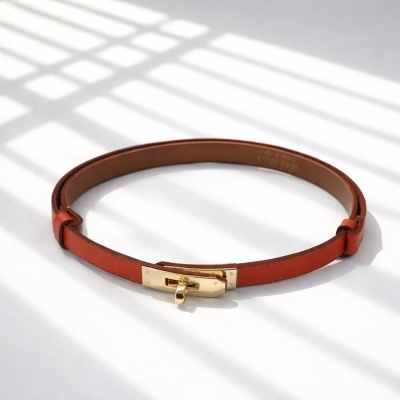 Cinto de pele castanha com fivela dourada sobre superfície branca