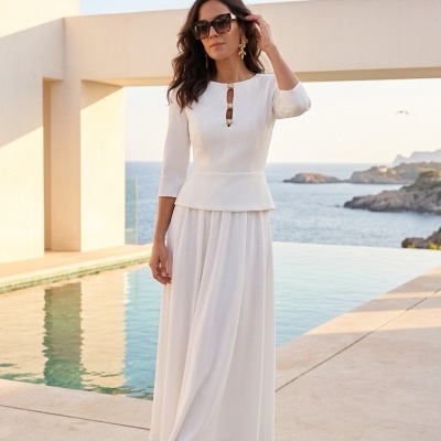 Mulher com vestido branco comprido e sandálias nude perto de piscina com mar ao fundo
