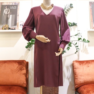 Vestido roxo elegante exibido em manequim num ambiente interior com sofás laranja e posters na parede