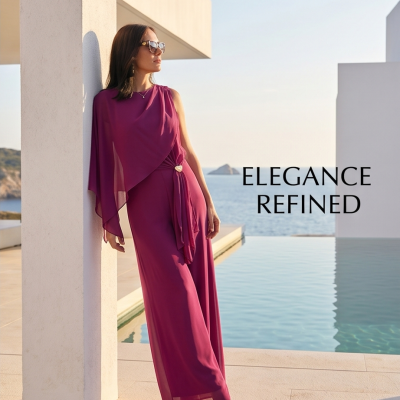 Mulher com vestido magenta longo junto a piscina com vista para o mar