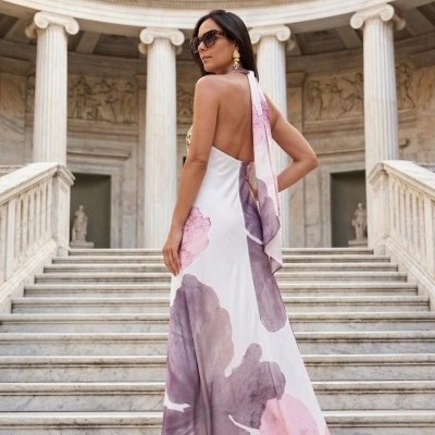 Mulher de vestido longo floral com decote costas nuas em escadaria clássica de mármore