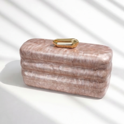 Bolsa de mão nude marmoreada com fecho dourado sobre superfície branca