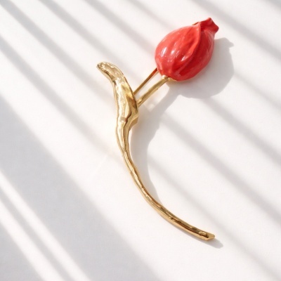 Penteado dourado em forma de flor com botão vermelho.