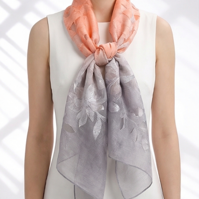 Lenço feminino cor de pêssego e cinza com padrão floral amarrado ao pescoço