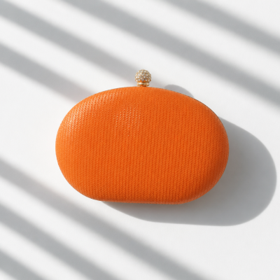 Mala de mão oval laranja com fecho dourado brilhante sobre fundo branco