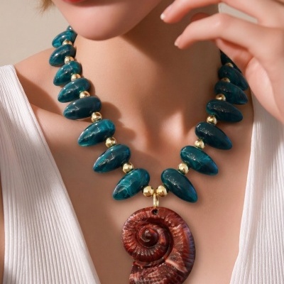 Colar com contas azuis, esferas douradas e pendente vermelho em espiral