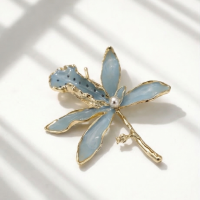 Broche em forma de flor azul com contorno dourado e pérola no centro