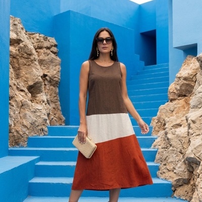 Vestido midi tricolor castanho branco e tijolo com sandálias e clutch com fundo azul e rochas