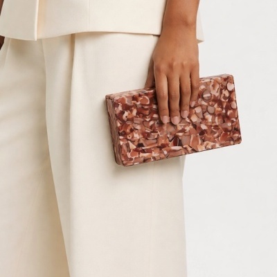 Clutch retangular castanha com padrão marmoreado e roupa branca de tecido liso