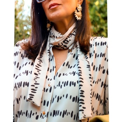 Blusa branca com manchas pretas, brincos dourados e óculos escuros
