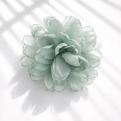 Flor artificial verde claro translúcida sobre fundo branco com sombras