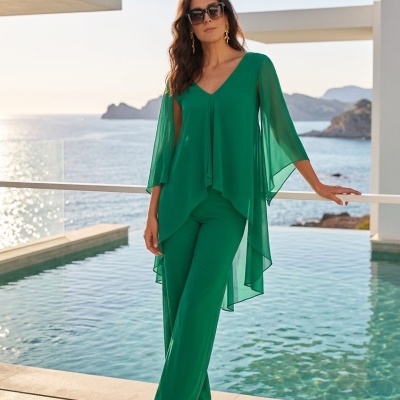Mulher com conjunto verde elegante junto a piscina com vista para o mar
