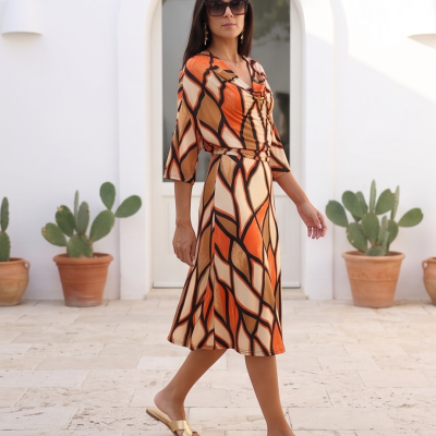 Vestido midi geométrico laranja com cinto em ambiente exterior com plantas em vasos