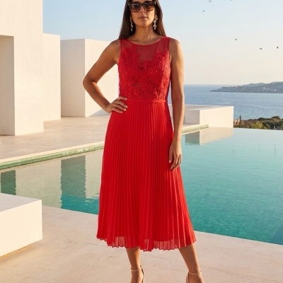 Vestido midi vermelho com renda e saia plissada perto de piscina com vista para o mar