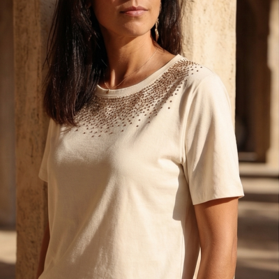 T-shirt bege claro com pedras decorativas na parte superior usada por mulher com óculos escuros