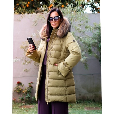 Mulher com casaco acolchoado verde-oliva com capuz de pelo e calças roxas