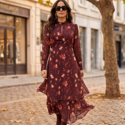 Mulher a usar vestido comprido castanho com padrão leve e botas em rua com calçada de pavê