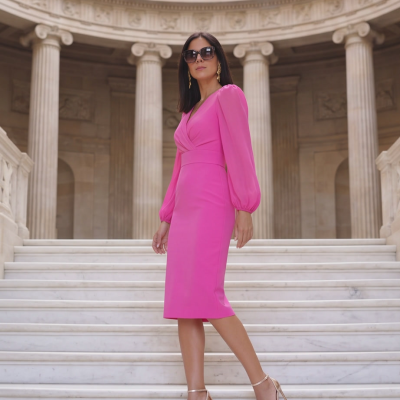 Mulher de vestido rosa e sandálias douradas numa escadaria de mármore