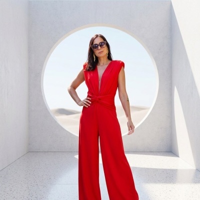 Mulher com macacão vermelho e óculos escuros num cenário minimalista