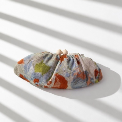 Carteira estampada azul, verde e laranja com fecho metálico e bolas rosas