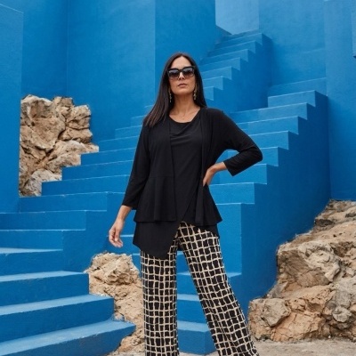 Mulher com camisola preta, calças quadriculadas e botins pretos em escadaria azul