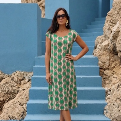 Mulher em vestido verde com padrão geométrico posando em escadaria azul ao ar livre