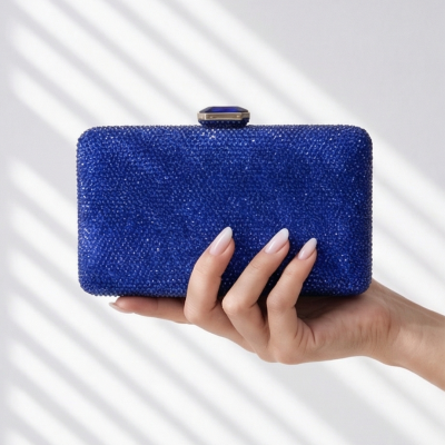 Carteira de mão azul brilhoso com fecho decorativo segurada por uma mão feminina