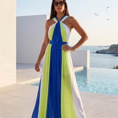 Mulher com vestido longo azul, verde-limão e branco, sandálias azuis e verdes, de pé perto de piscina ao ar livre