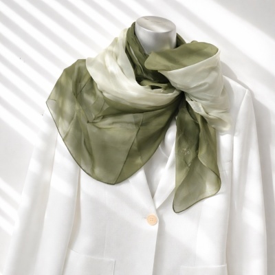 Lenço transparente verde-oliva e branco sobre blazer branco num manequim