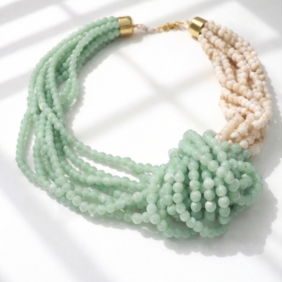 Colar de contas verdes e bege com fecho dourado em fundo branco