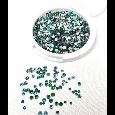 Caixa branca com pedras strass verdes e azuis sobre fundo branco