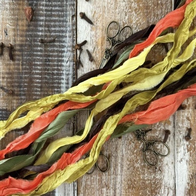 Fios de tecido coloridos sobre mesa de madeira com alicates.