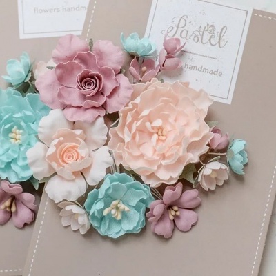 Cartões decorativos com flores artesanais em tons pastel sobre superfície branca