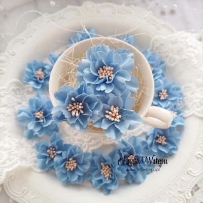 Flores artificiais azuis delicadas em chávena branca sobre prato branco decorativo