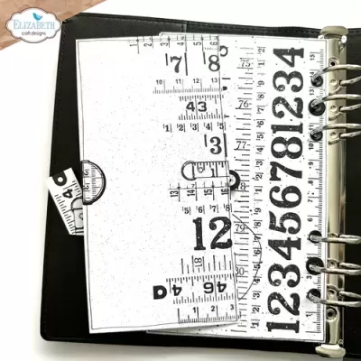 Agenda preta aberta com páginas decoradas com padrões de réguas e números