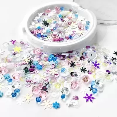 Lantejoulas coloridas em caixa redonda branca aberta