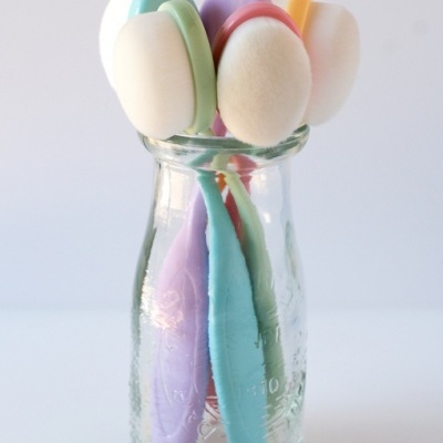 Frasco de vidro com cinco escovas coloridas de cabo pastel e cabeça branca macia