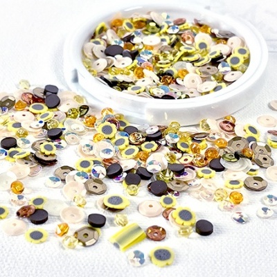 Lantejoulas coloridas em tons metálicos e amarelo sobre superfície branca