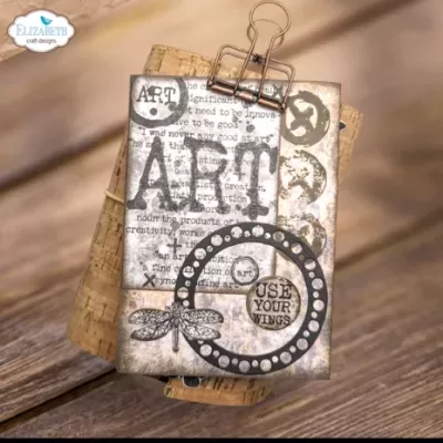 Etiqueta decorativa de papel envelhecido com texto e desenhos, pendurada em clipe sobre cortiça