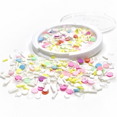 Confetis coloridos variados em superfície branca com tampa transparente ao lado