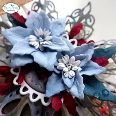 Flor artesanal azul com detalhes vermelhos e brancos sobre fundo floral metálico cinza