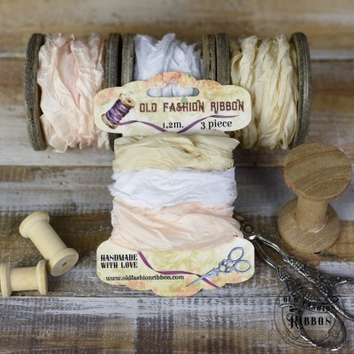 Fitas Old Fashion Ribbon em rolos de madeira, cores creme, branco e salmão em textura enrugada.
