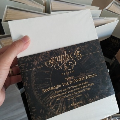 Álbum retangular marfim da marca graphic 45 com embalagem plástica e etiqueta preta com texto dourado