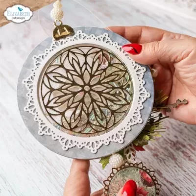 Pendurante decorativo circular com padrão floral e moldura branca detalhada.