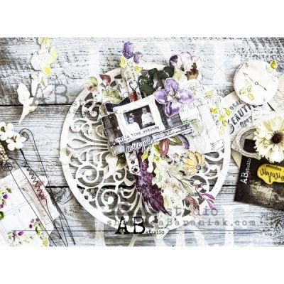 Conjunto decorativo de scrapbooking com flores, papel recortado, e fotografia em fundo de madeira cinza.