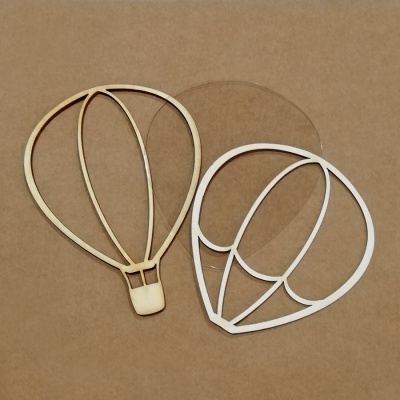 Três moldes em forma de balão, dois de madeira e um de plástico transparente, sobre fundo castanho.