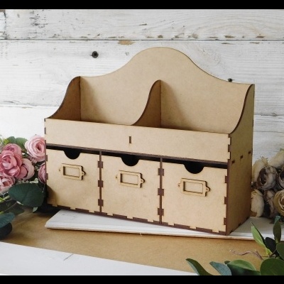 Organizador de madeira com três gavetas e divisória dupla rodeado por flores artificiais