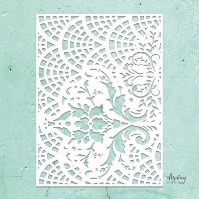 Papel branco recortado com padrão ornamental sobre parede verde clara
