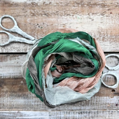 lenço colorido enrolado com tesoura ao fundo em superfície de madeira