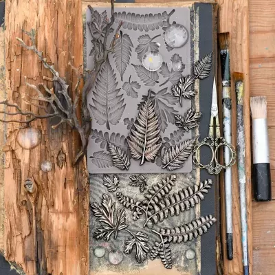 Moldes de silicone com formas de folhas e ferramentas de pintura sobre mesa de madeira